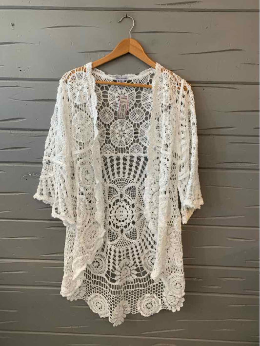 White crochet open-front cardigan with scalloped edges and loose three-quarter sleeves.
