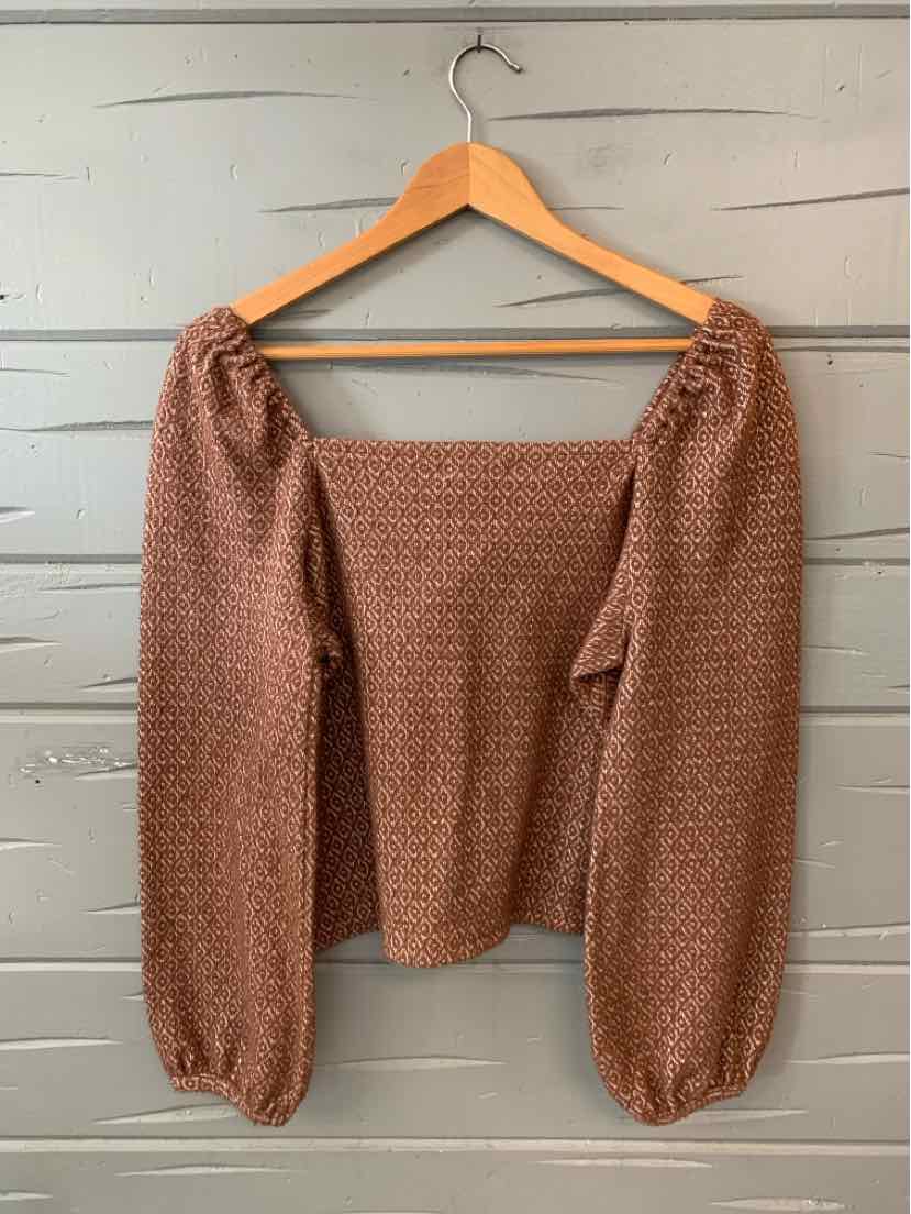 Tan long-sleeve blouse with puffed sleeves and textured pattern on fitted bodice.