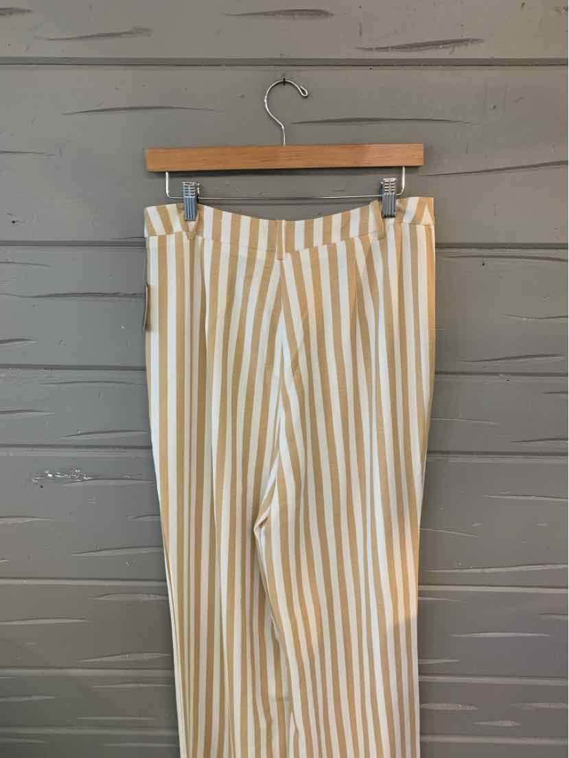 Tan and white vertical striped wide-leg pants hanging on wooden hanger against gray wall.