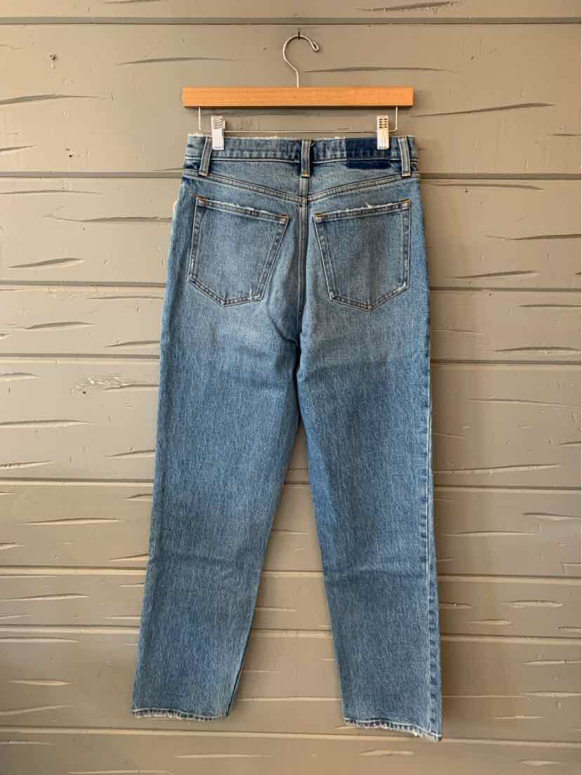 Medium-wash blue denim jeans with a straight-leg cut, back pockets, and a brown waistband patch.