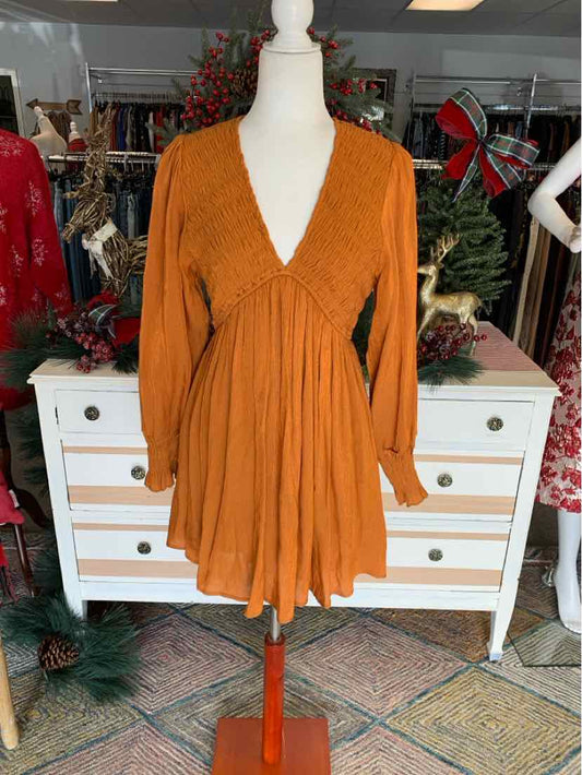 Peach orange long-sleeve dress with deep V-neck and gathered empire waist on mannequin.