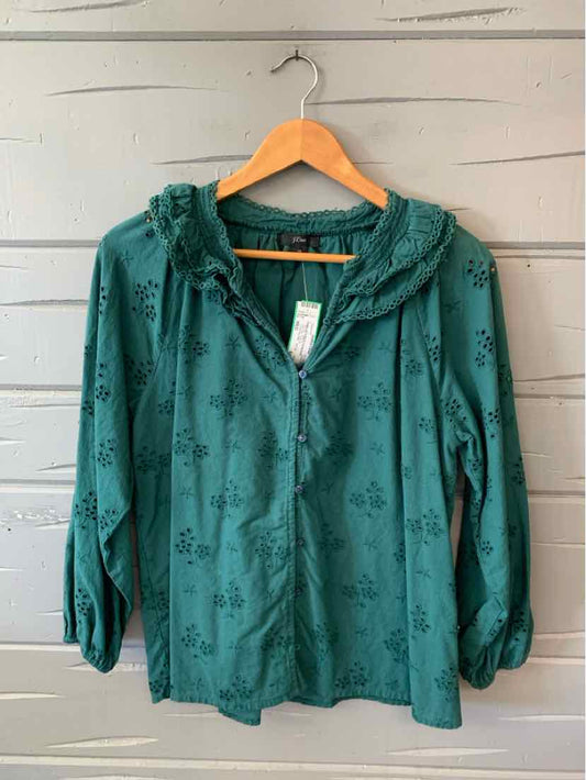 Green long-sleeve blouse with eyelet floral pattern, front zipper, and ruffled neckline.