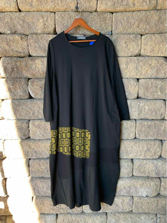 Black Alembika long-sleeve tunic dress with a relaxed fit and geometric yellow accents near the hem.