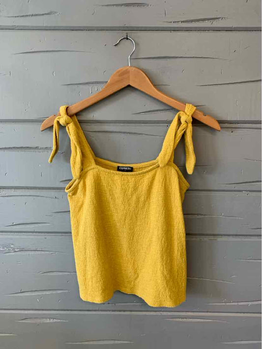 Yellow sleeveless knit tank top with adjustable tie straps on wooden hanger.