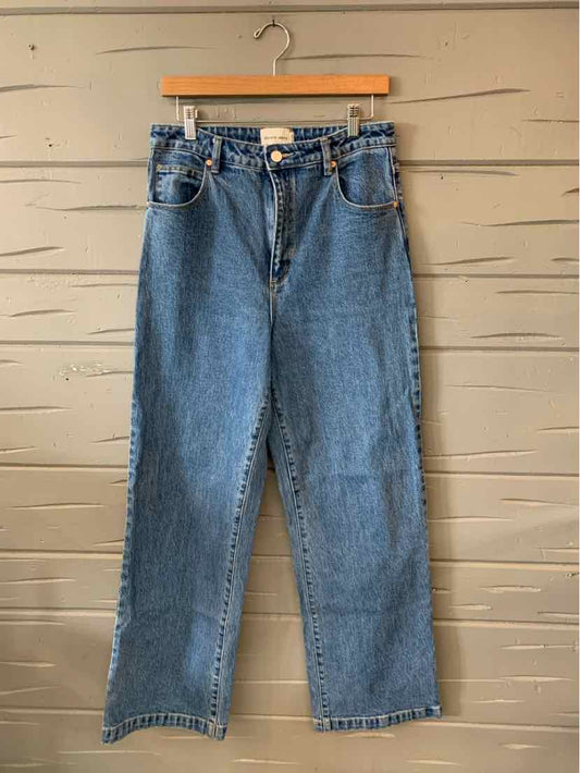 High-waisted blue denim jeans with a straight leg fit and five-pocket design hanging on wooden hanger.