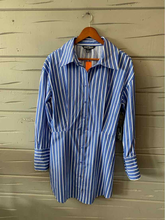 Blue and white vertical striped medium-length shirt dress with long sleeves and pointed collar on wooden hanger.