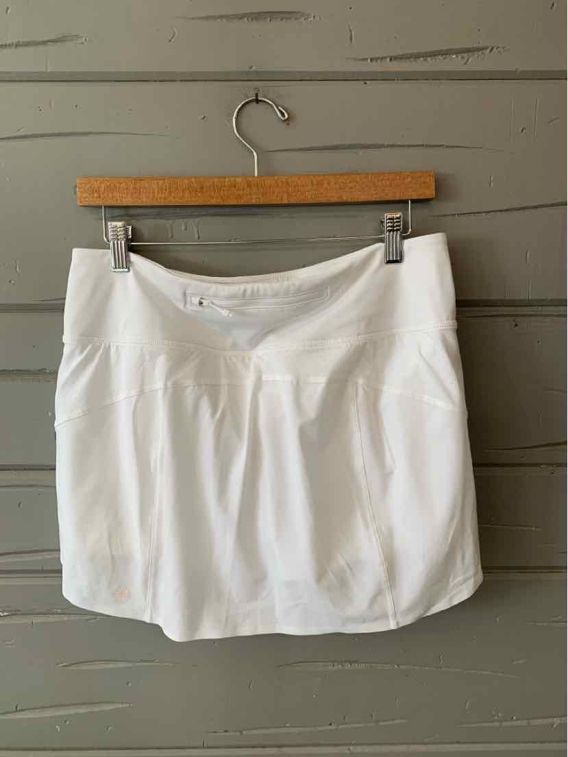 White athletic mini skirt with stitched waistband and subtle pleats, hanging on wooden hanger.