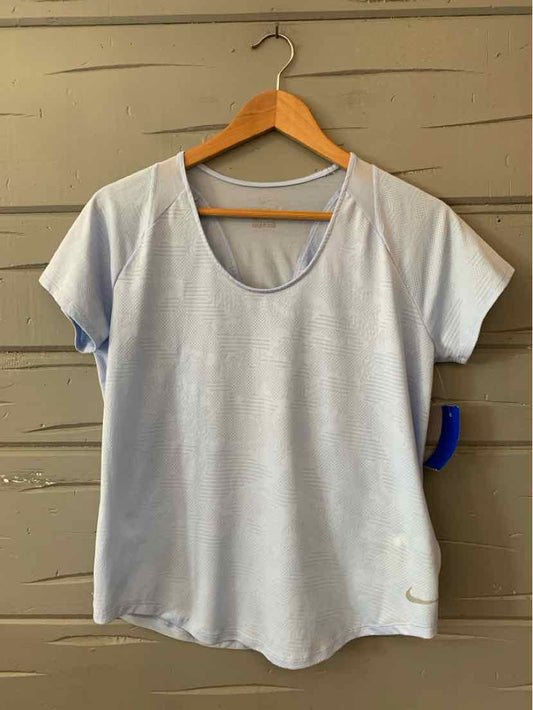 Light blue Nike women's short-sleeve athletic shirt with scoop neck and small swoosh logo near hem.
