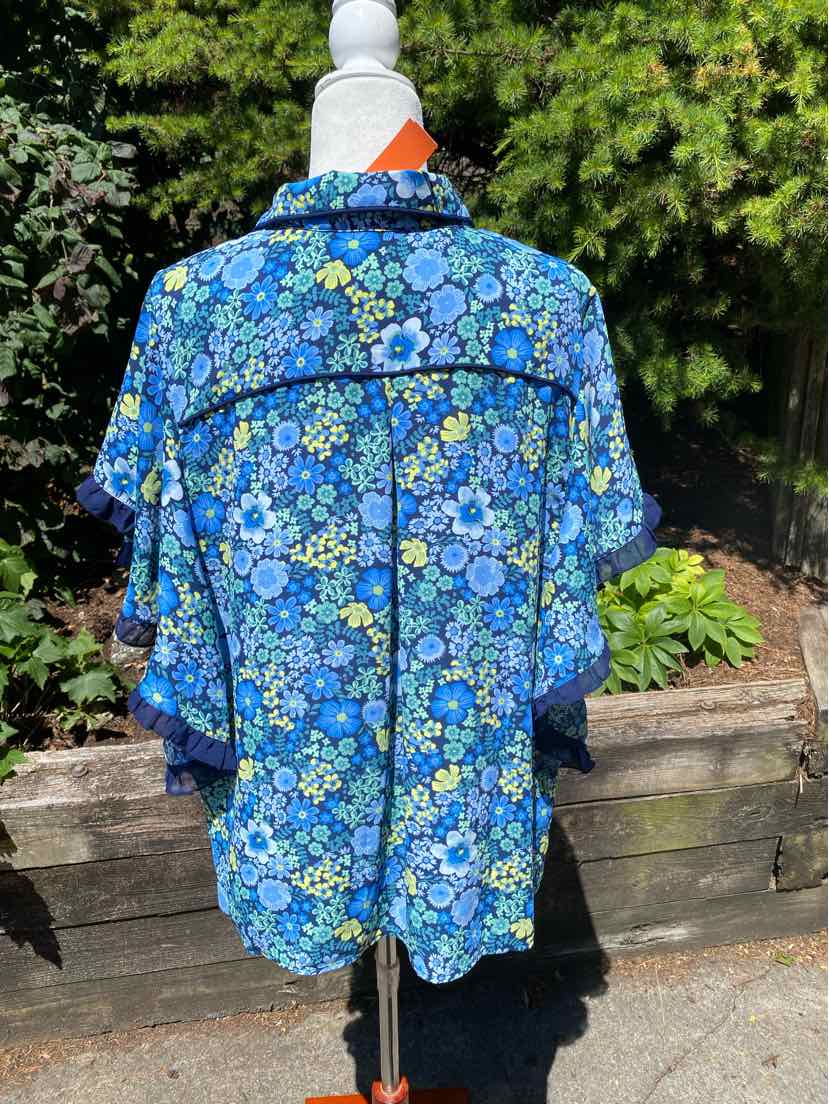 Blue floral short-sleeve felt blouse with loose fit and black piping on back seams.