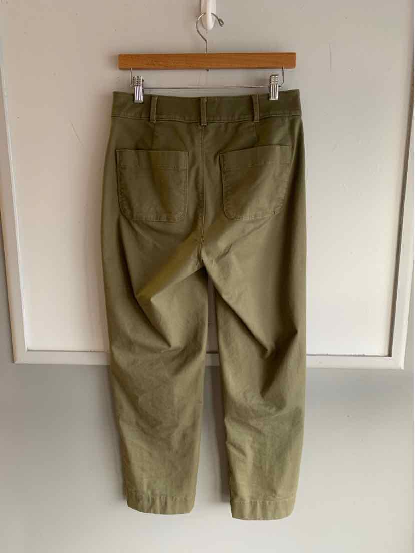 Olive green cotton pants with back patch pockets and belt loops, hanging on wooden hanger.