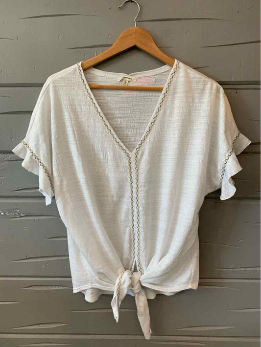 White short-sleeve blouse with V-neck, ruffled sleeves, and front tie hem on wooden hanger.