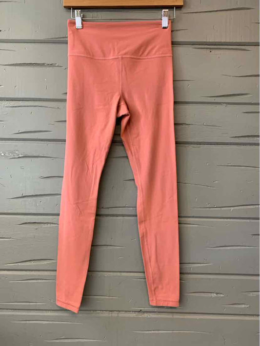 Coral pink high-waisted full-length leggings with flat seams and smooth fabric texture.