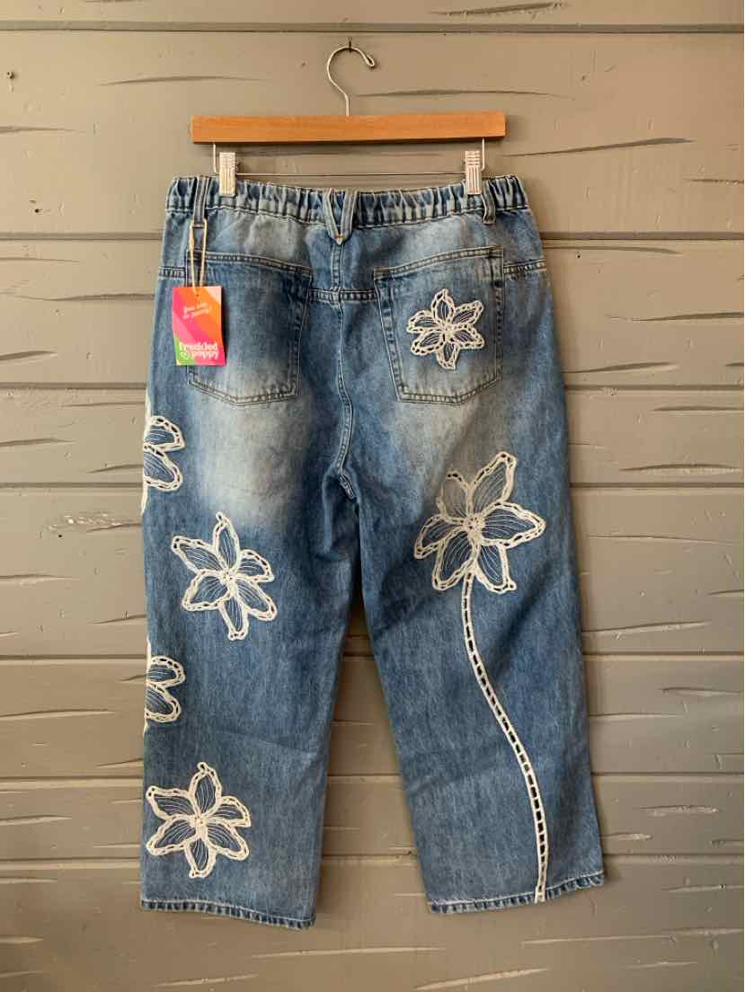 Light blue denim jeans with white embroidered freckled poppy flowers and a loose fit, size large.