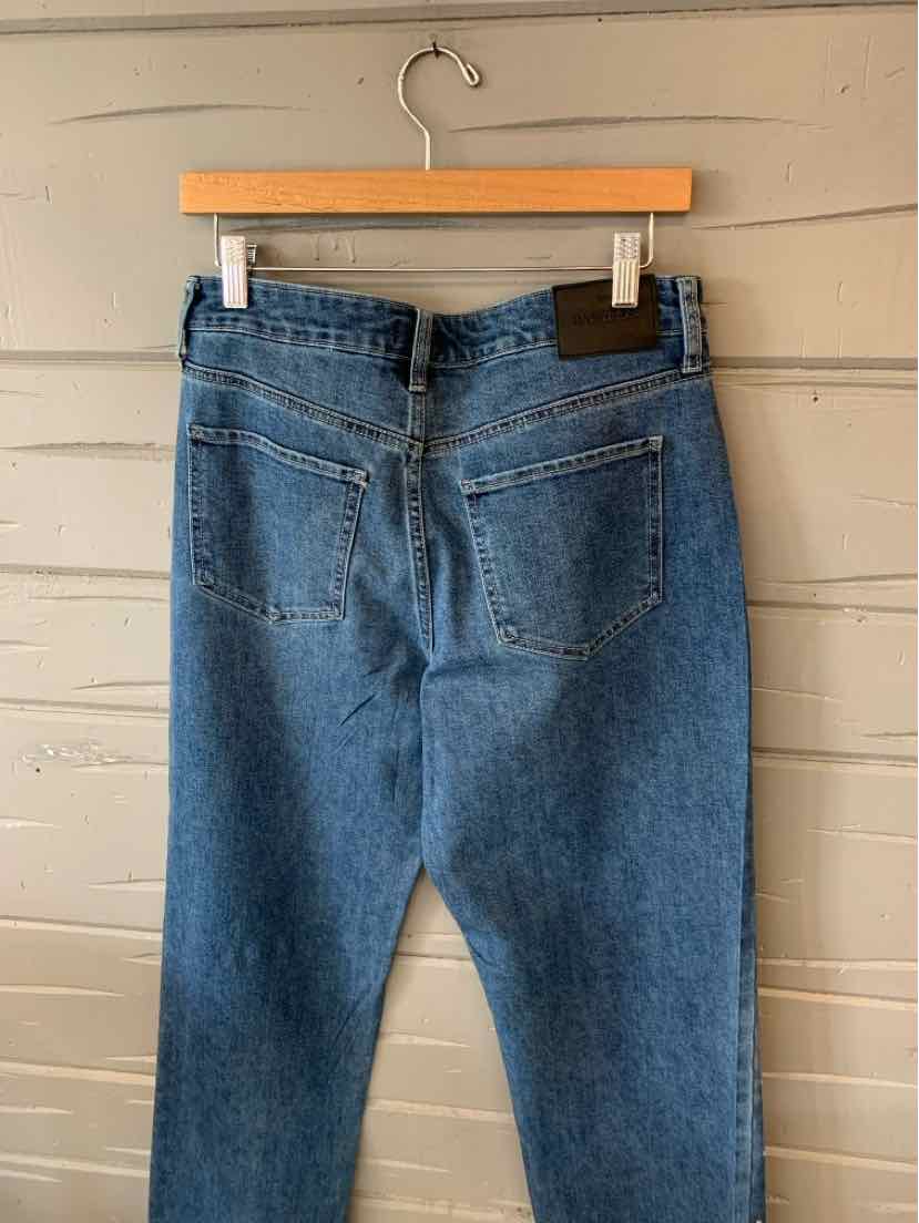 Blue denim jeans with high-rise back pockets and brown leather patch on waistband.