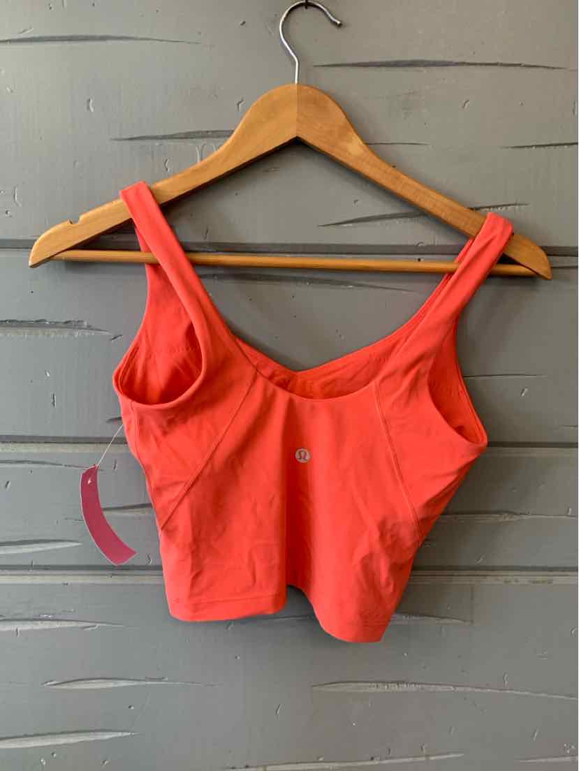 Coral cropped tank top with wide straps and scoop neck, featuring small reflective Lululemon logo at center front.