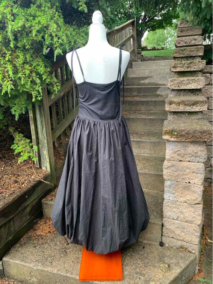 Black sleeveless midi dress with spaghetti straps and gathered skirt on mannequin outdoors.