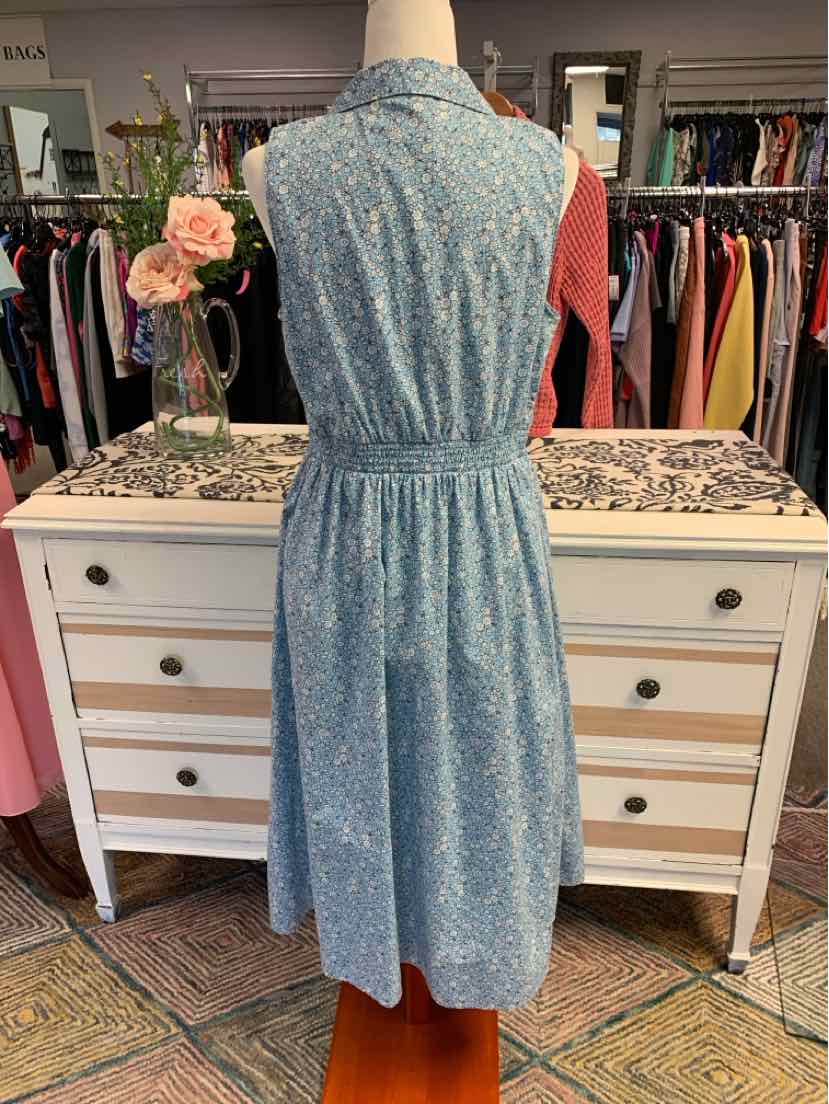 Blue floral sleeveless midi dress with cinched waist and collared neckline on mannequin.
