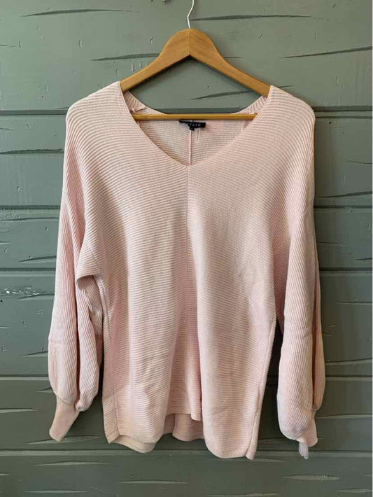 Light pink long-sleeve sweater with a V-neck and ribbed cuffs on wooden hanger.