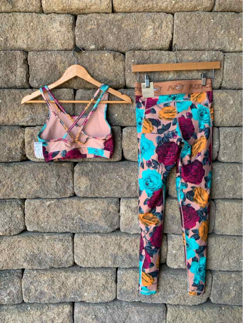 Floral print sports bra with crisscross back straps and matching high-waisted leggings in multicolor pattern.