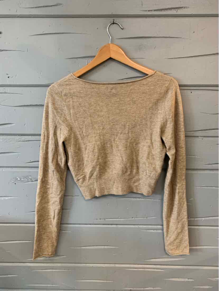 Tan long-sleeve cropped knit sweater with a boat neckline on wooden hanger.