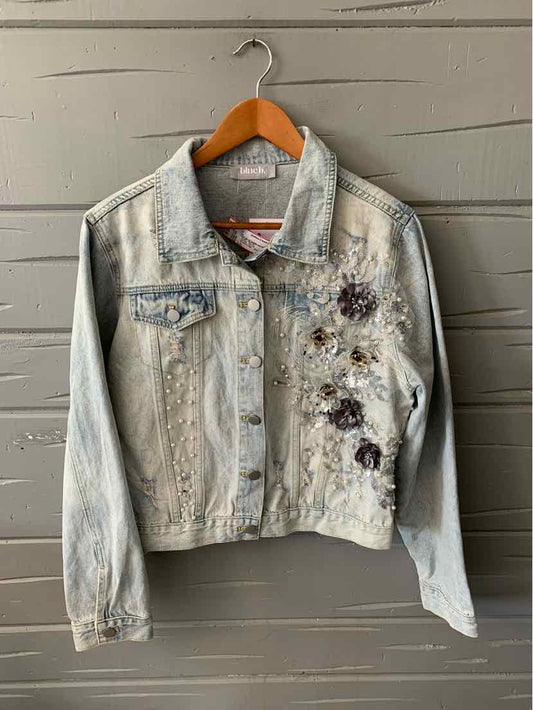 Light wash denim jacket with floral embroidery and button-front closure in large size.