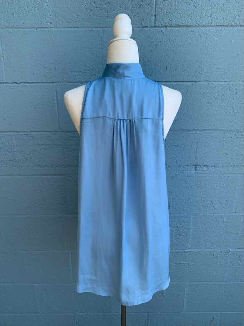 Light blue sleeveless blouse with high collar and back yoke detail on mannequin against gray wall.