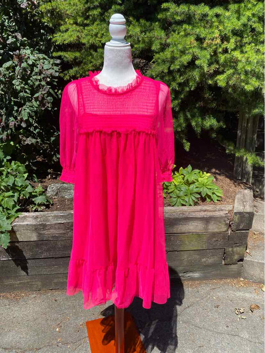 Bright pink midi dress with long sheer sleeves, ruffled collar, and flowy skirt paneling.