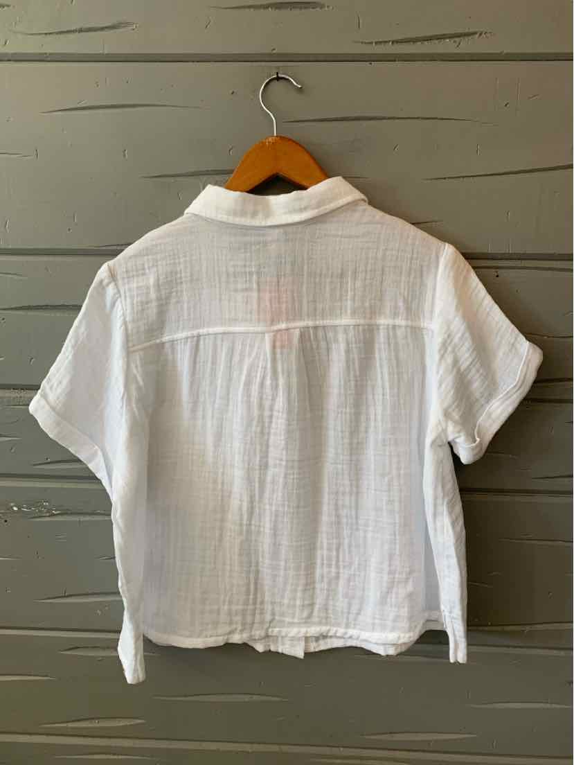 White short-sleeve cotton blouse with a textured pattern and loose fit on wooden hanger.