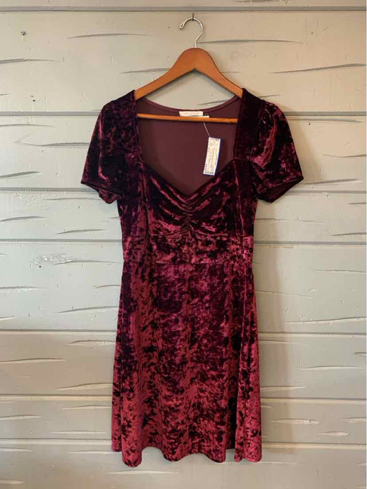 Burgundy and black velvet Urban Outfitters dress with a scoop neckline and short sleeves, hanging on a wooden hanger.