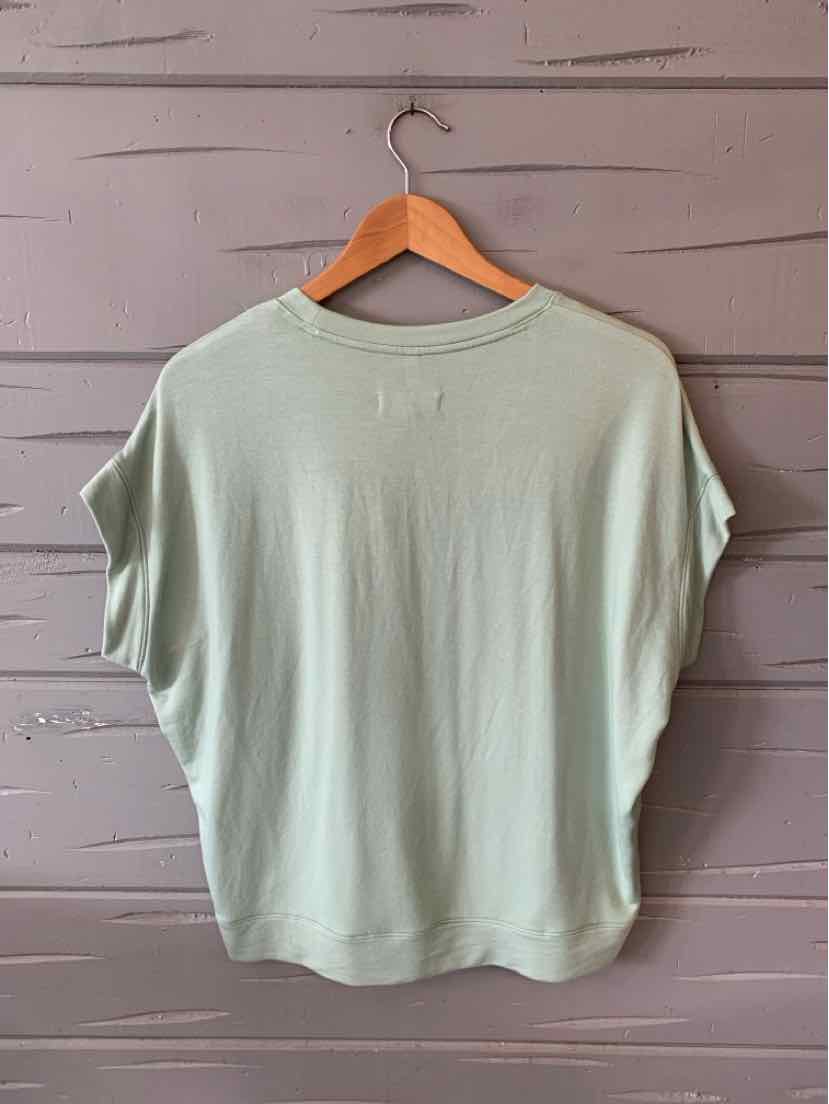Light green oversized short-sleeve cotton T-shirt with a round neckline on a wooden hanger.