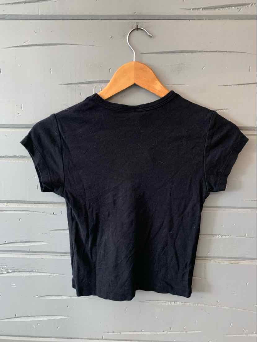 Black short-sleeve fitted t-shirt with crew neck hanging on wooden hanger against white wooden wall.