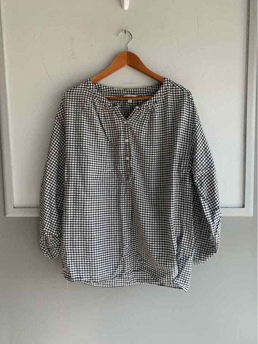 Black and white gingham checkered long sleeve blouse with buttoned neckline on wooden hanger.