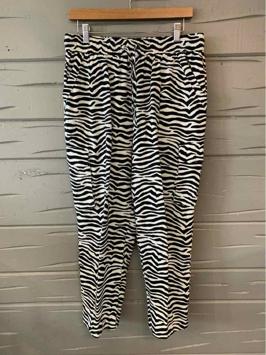 Black and white zebra stripe jogger pants with elastic waistband and cuffs hanging on wooden hanger.