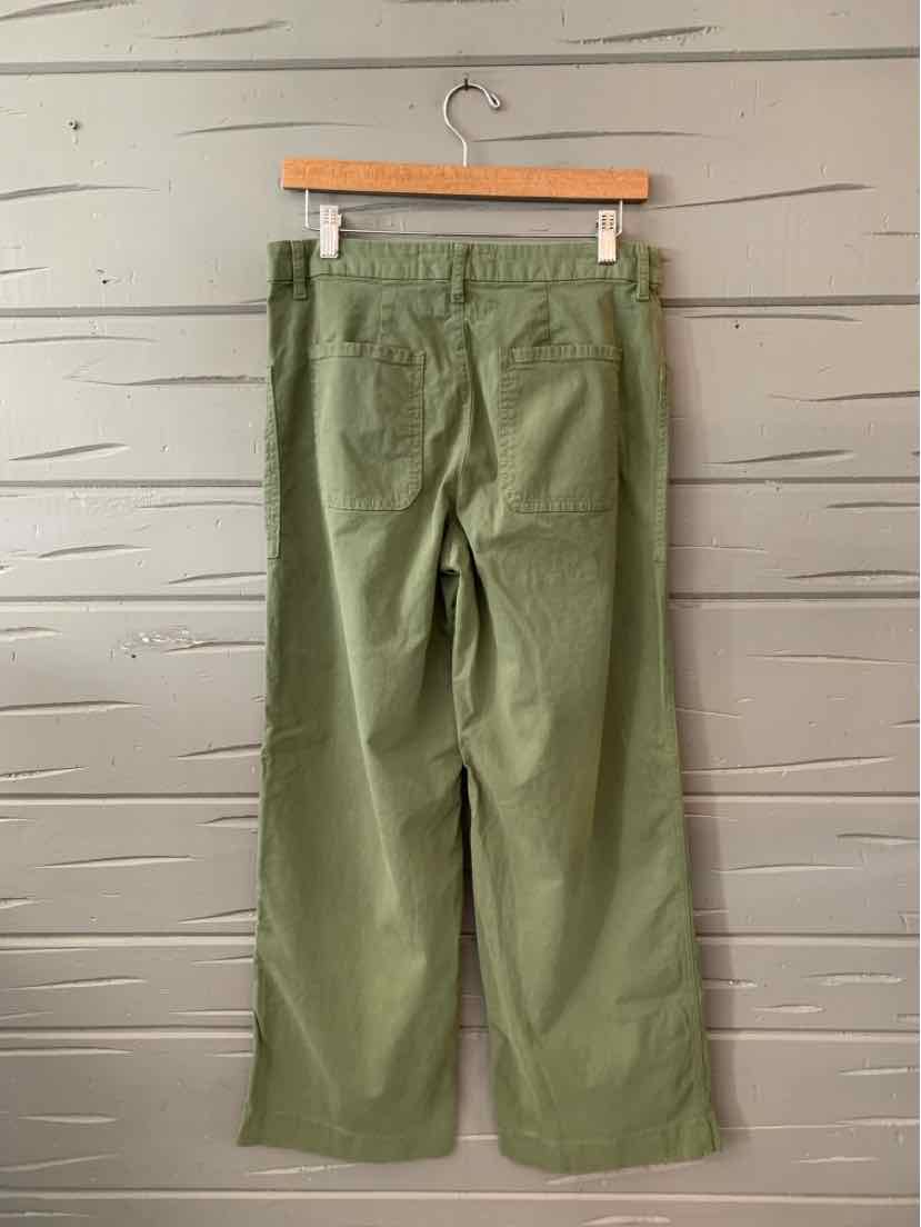 Olive green relaxed-fit pants with wide legs and back patch pockets hanging on wooden hanger.