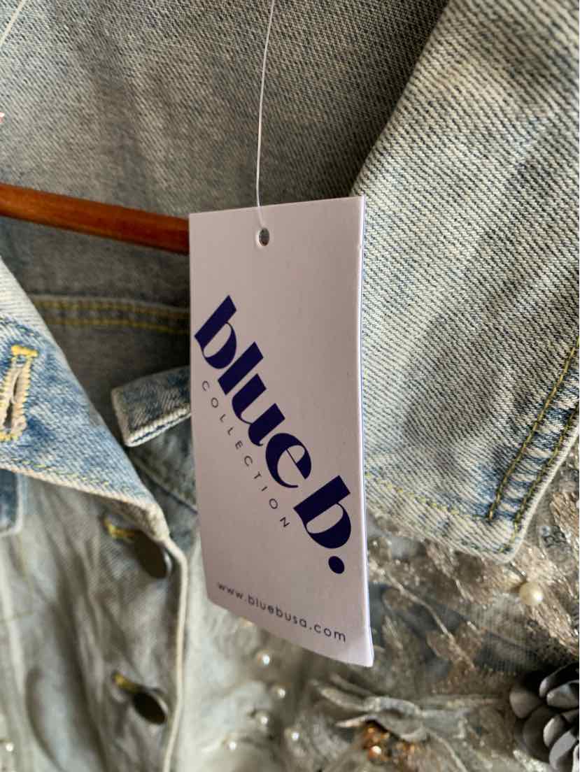 Light blue denim jacket with metal buttons and a white Blue B branded hang tag.