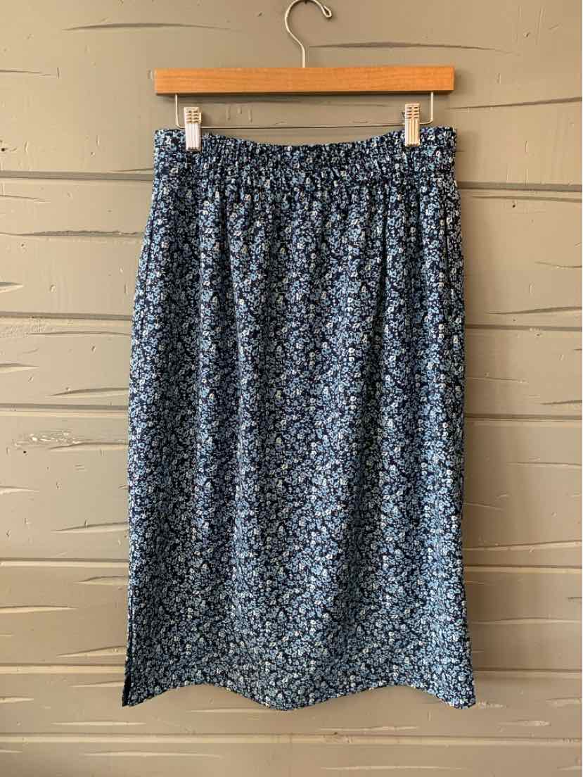Blue floral midi skirt with elastic waistband and soft fabric hanging on wooden hanger.