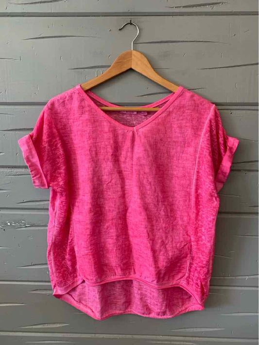 Bright pink short-sleeve loose-fit top with rolled cuffs and rounded hem on wooden hanger.