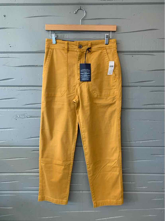 Mustard yellow Gap women’s straight-leg pants with a button closure, front pockets, and attached tags.