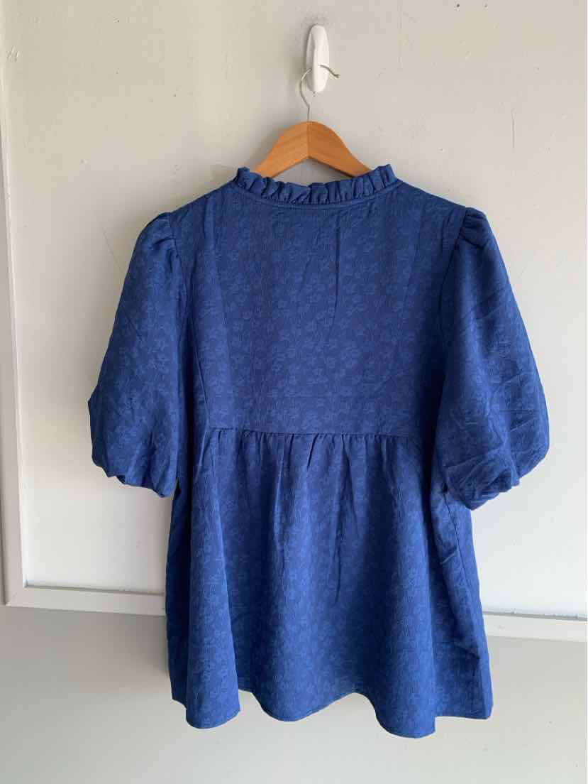 Blue textured blouse with puffed elbow-length sleeves and ruffled collar on wooden hanger.
