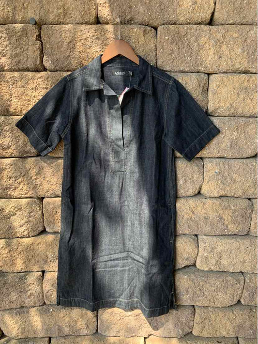 Black short-sleeve collared polo dress with button placket on wooden hanger against stone wall.