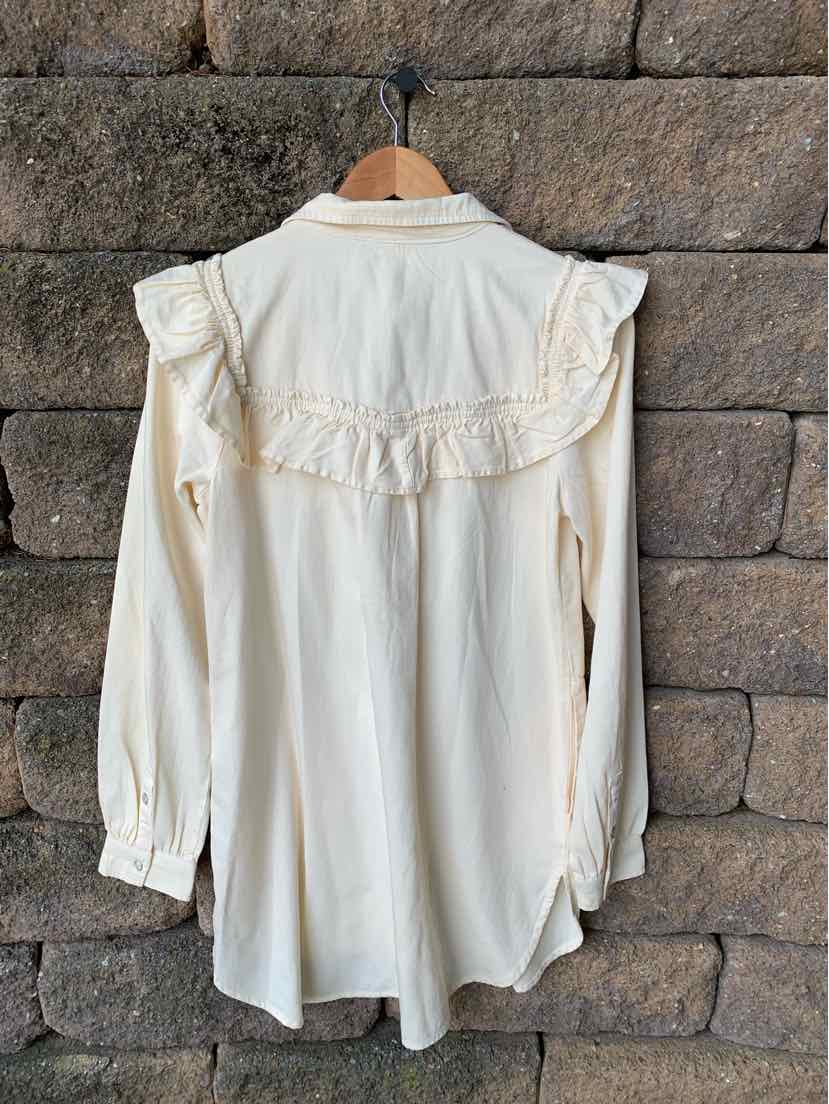 Cream-colored long sleeve blouse with ruffled yoke and pleated cuffs, lightweight fabric.