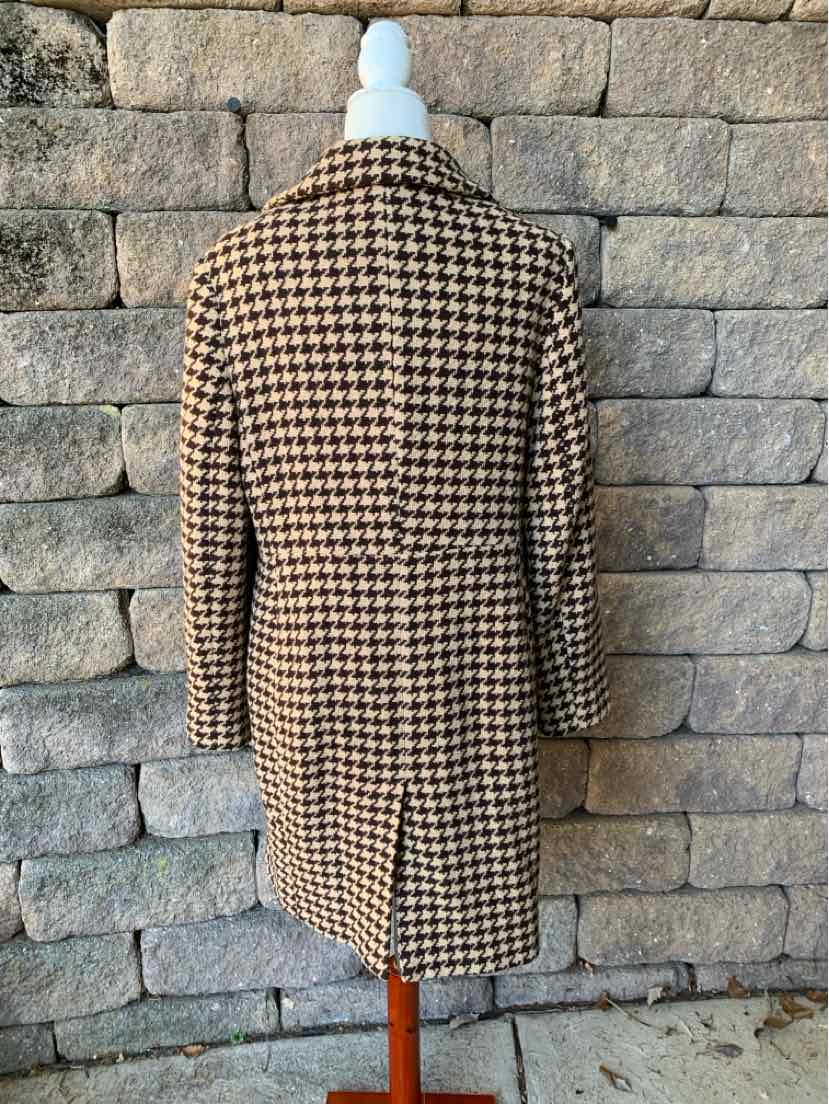 Women’s brown and cream houndstooth coat with a long, tailored silhouette and notched lapels.