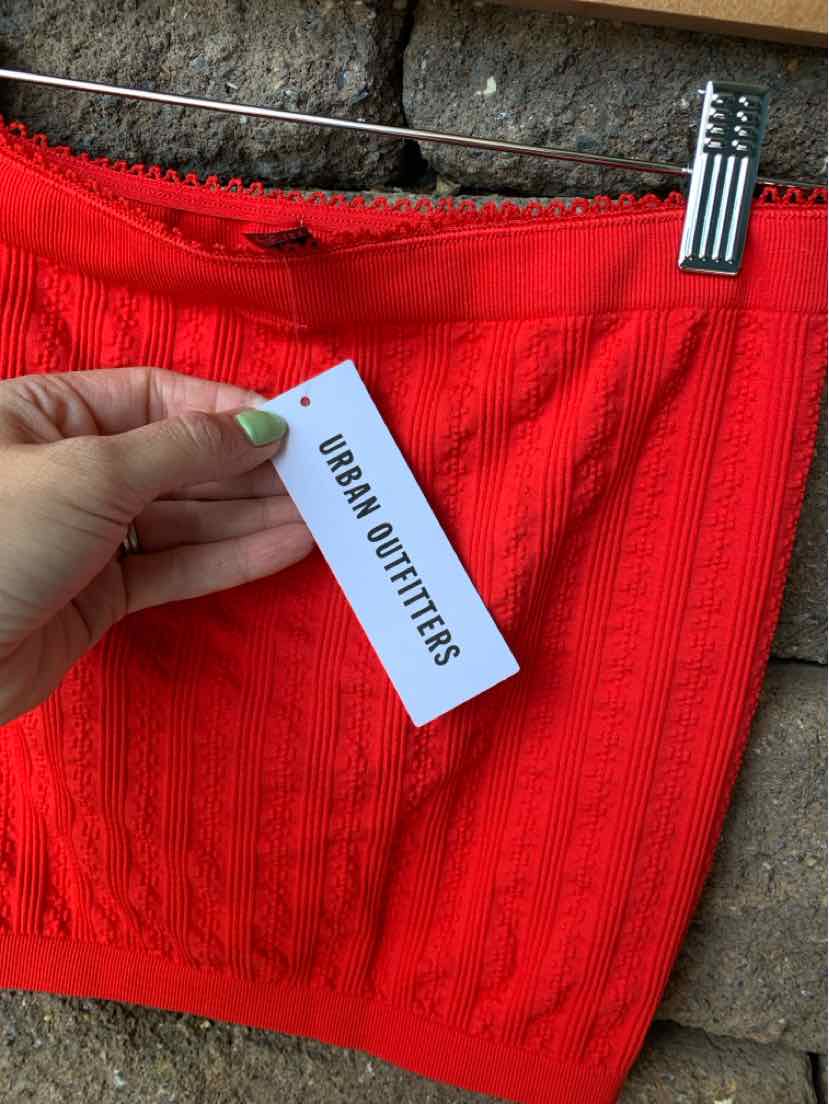Bright red knit skirt with ribbed pattern and scalloped hem, labeled size M/L by Urban Outfitters.