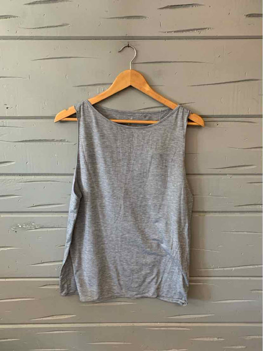 Gray sleeveless tank top with side slits on wooden hanger against gray wooden wall.