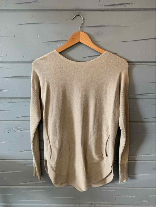 Tan long-sleeve knit sweater with a crew neckline and relaxed fit hanging on wooden hanger.