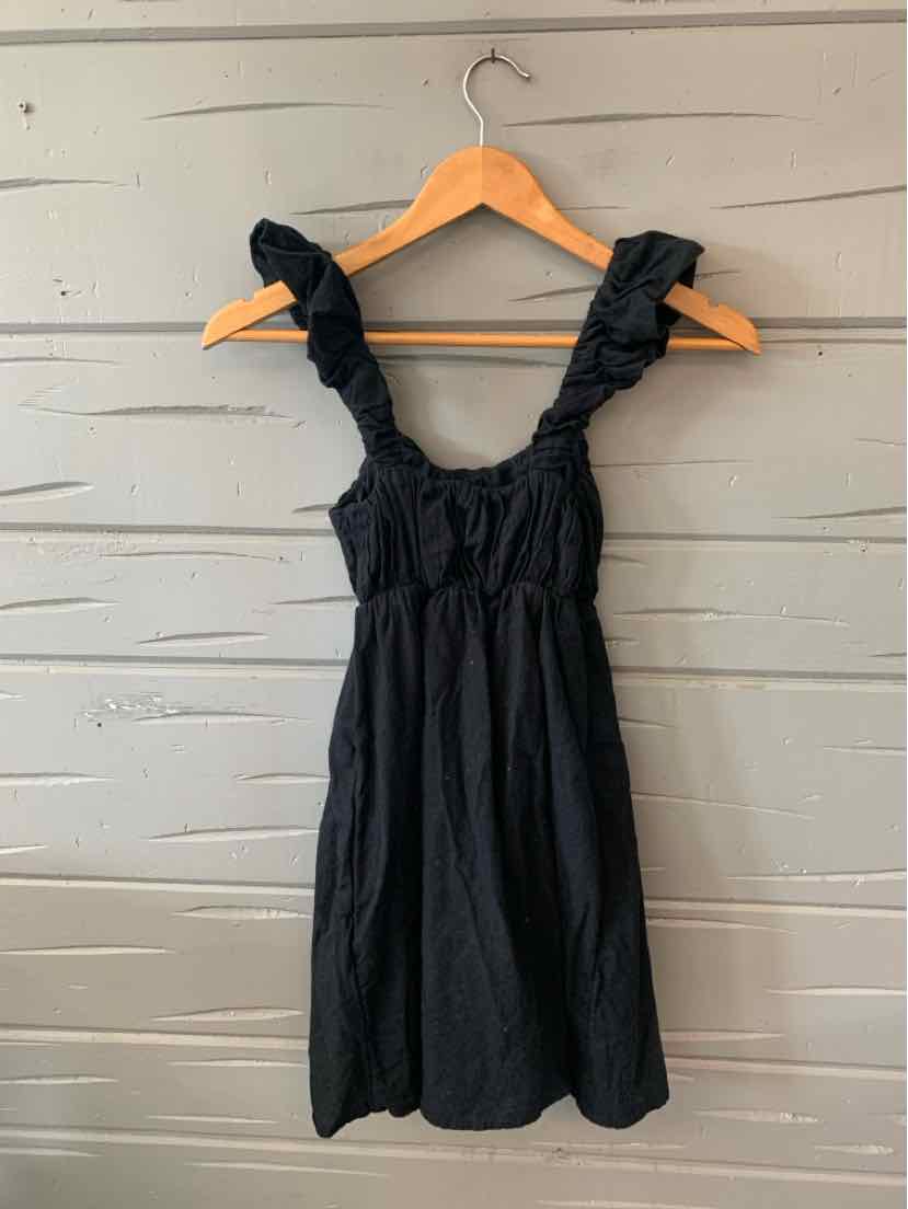 Black sleeveless dress with ruffled straps and gathered bodice, knee-length, lightweight fabric.