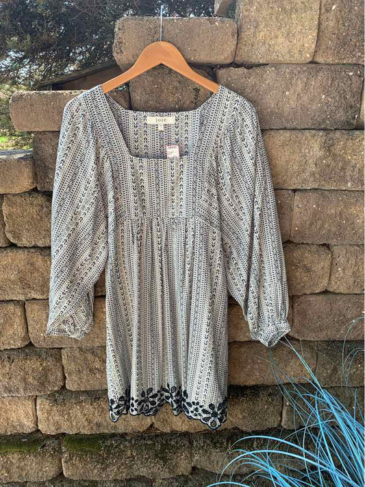 Light melon blouse with puffed long sleeves and black floral embroidery along the hem.