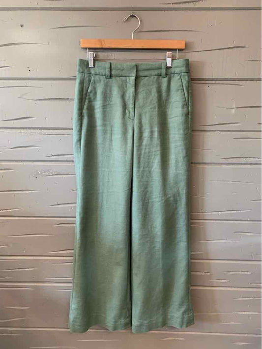 Light green high-waisted wide-leg trousers with belt loops hanging on wooden hanger.