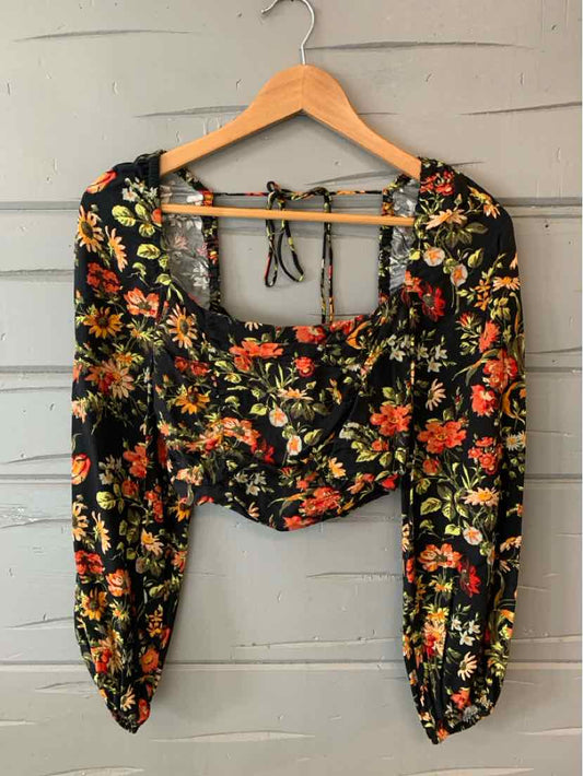 Black floral crop top with long puffed sleeves and square neckline on wooden hanger.
