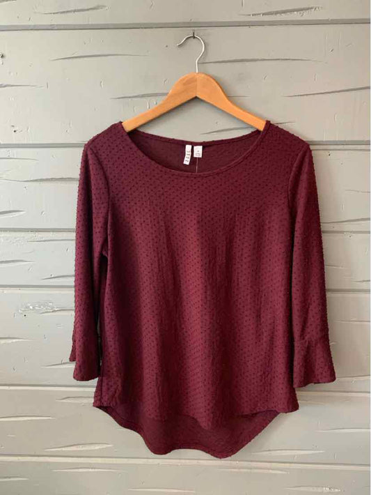 Burgundy textured long-sleeve blouse with scoop neck and slightly flared sleeves on wooden hanger.